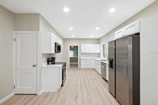 kitchen featuring white cabinets, light wood-type flooring, stainless steel appliances, and sink