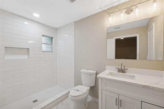 bathroom with tiled shower, vanity, and toilet