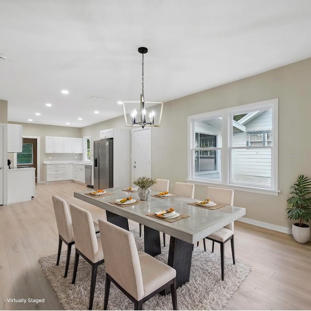 dining area with light wood-type flooring and an inviting chandelier