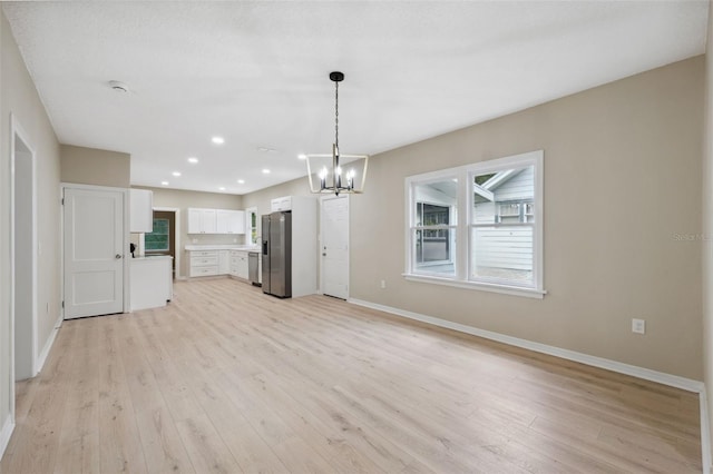 kitchen featuring hanging light fixtures, light hardwood / wood-style flooring, a notable chandelier, white cabinets, and appliances with stainless steel finishes