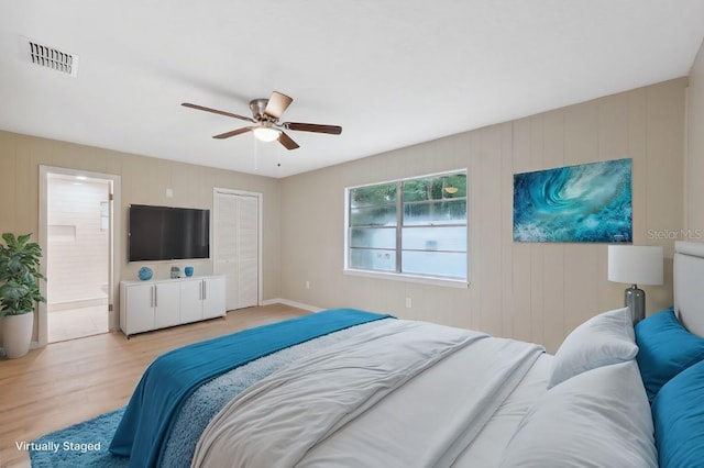 bedroom with light wood-type flooring, connected bathroom, a closet, and ceiling fan