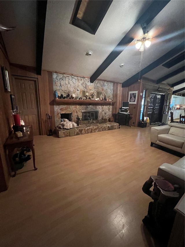 living room featuring a fireplace, wooden walls, ceiling fan, lofted ceiling with beams, and hardwood / wood-style floors