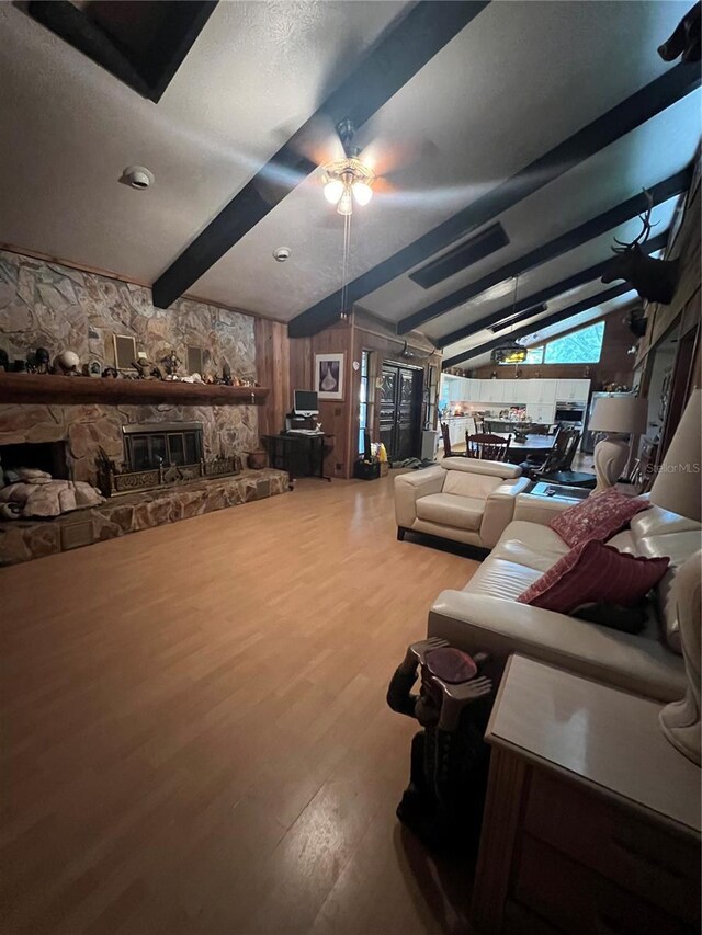 living room featuring a textured ceiling, lofted ceiling with beams, hardwood / wood-style floors, ceiling fan, and a fireplace