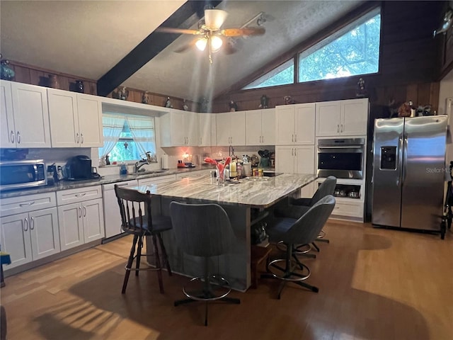 kitchen featuring ceiling fan, stainless steel appliances, a breakfast bar, and a center island