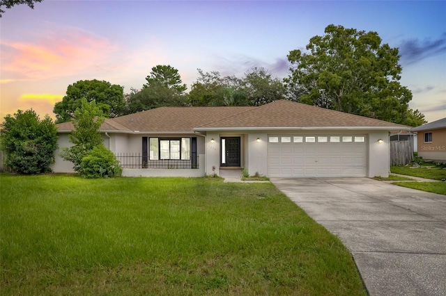 single story home featuring a garage and a lawn