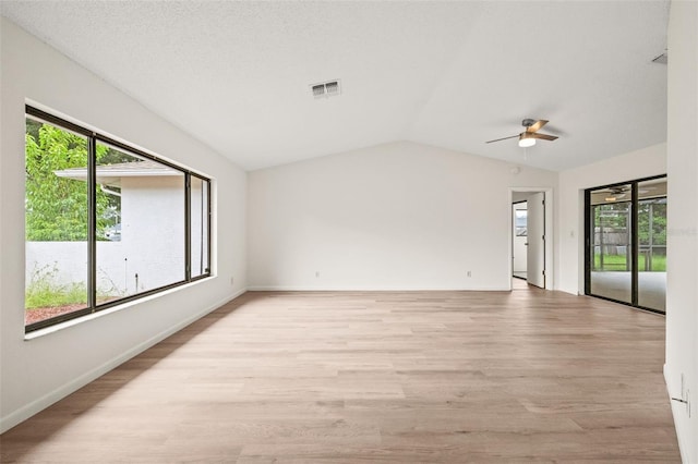 spare room featuring light wood-type flooring, vaulted ceiling, and a wealth of natural light