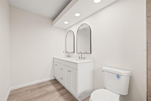 bathroom with toilet, vanity, and hardwood / wood-style flooring