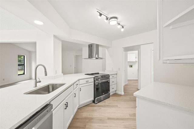 kitchen featuring sink, white cabinetry, light wood-type flooring, stainless steel appliances, and wall chimney range hood