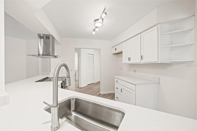 kitchen featuring range hood, sink, white cabinetry, light hardwood / wood-style floors, and rail lighting