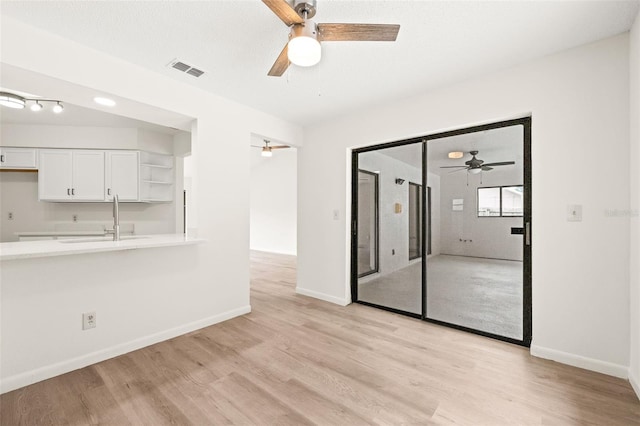 interior space featuring ceiling fan, sink, and light hardwood / wood-style flooring