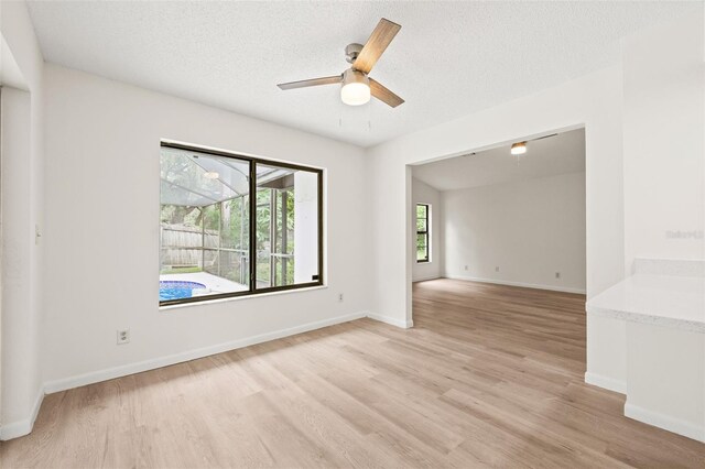 empty room featuring ceiling fan, light wood-type flooring, and a textured ceiling