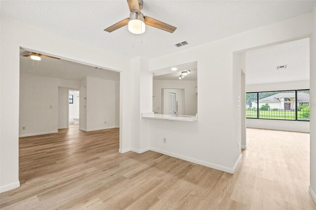 empty room with light hardwood / wood-style flooring, a textured ceiling, and ceiling fan