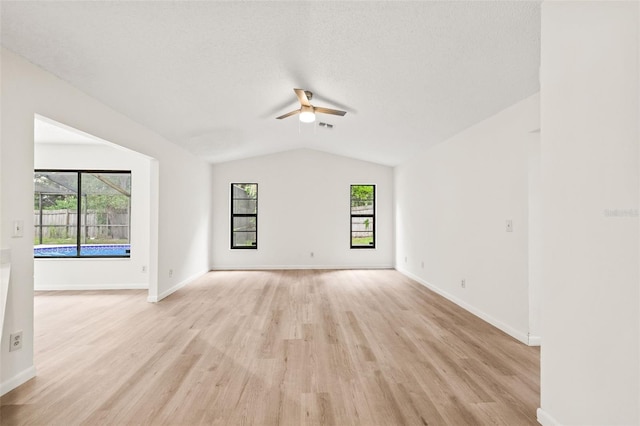 unfurnished living room featuring light hardwood / wood-style flooring, ceiling fan, vaulted ceiling, and a textured ceiling