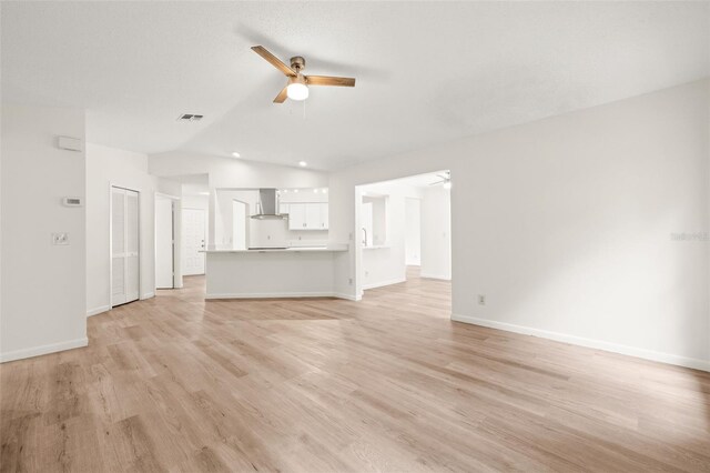 unfurnished living room with ceiling fan, light wood-type flooring, and lofted ceiling