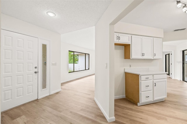 kitchen featuring light wood-type flooring, a textured ceiling, and white cabinets