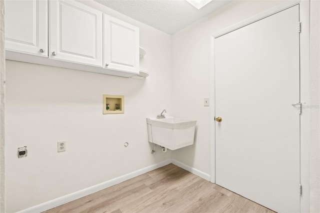 laundry room featuring cabinets, a textured ceiling, hookup for a washing machine, hookup for an electric dryer, and light hardwood / wood-style floors