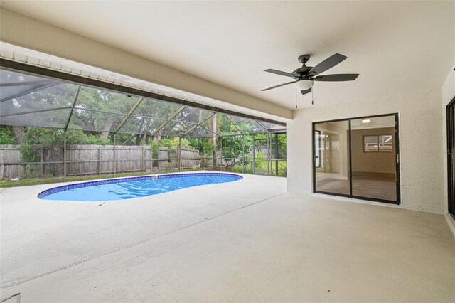 view of pool featuring a patio area, glass enclosure, and ceiling fan