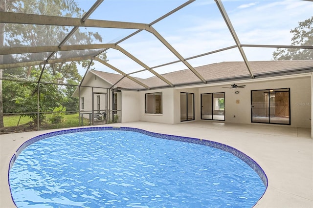 view of swimming pool featuring a patio, glass enclosure, and ceiling fan