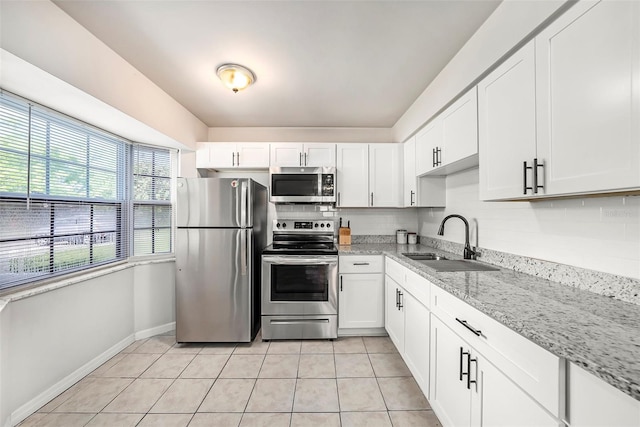 kitchen featuring appliances with stainless steel finishes, white cabinets, light tile patterned floors, and sink