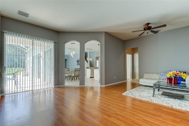 living room featuring ceiling fan with notable chandelier and hardwood / wood-style flooring