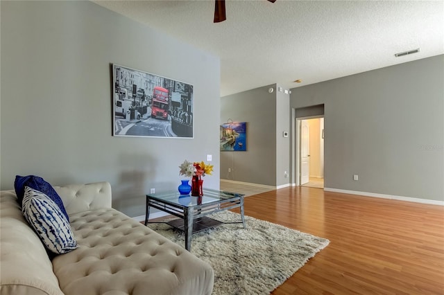 living room with a textured ceiling, hardwood / wood-style floors, and ceiling fan