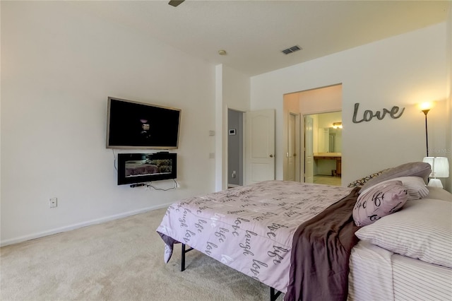 bedroom with connected bathroom and light colored carpet