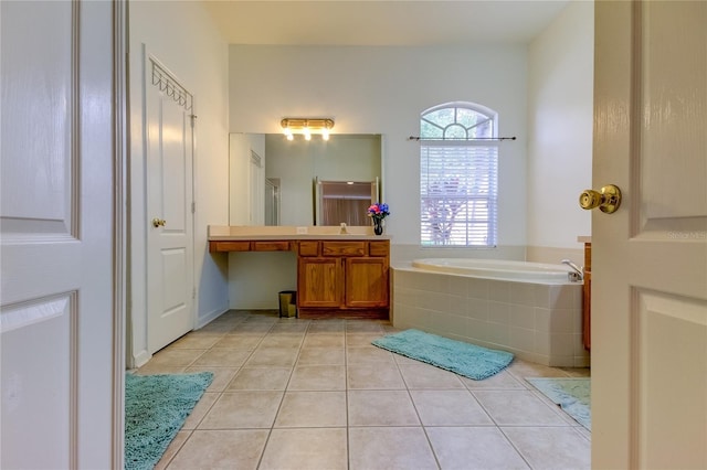 25954 Risen Star Dr, Wesley Chapel, FL 33544 - bathroom with a relaxing tiled tub, tile patterned floors, and vanity