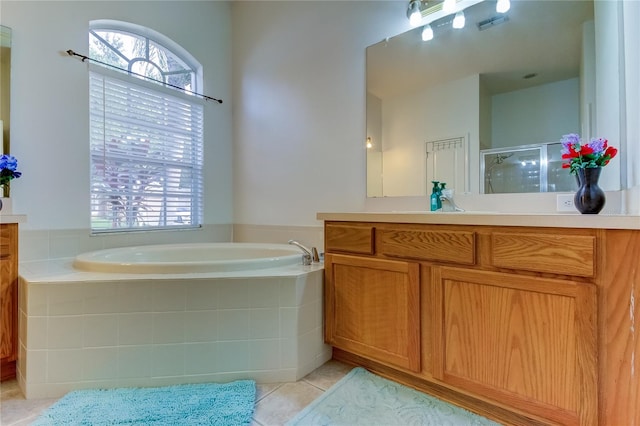 bathroom with tiled tub, tile patterned floors, and vanity