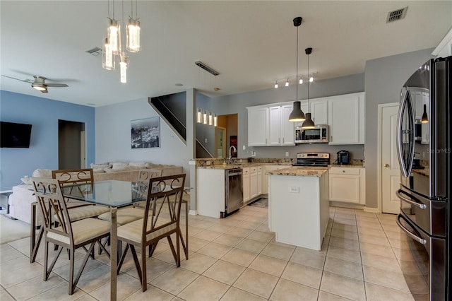 25954 Risen Star Dr, Wesley Chapel, FL 33544 - kitchen featuring light stone counters, decorative light fixtures, stainless steel appliances, and white cabinetry