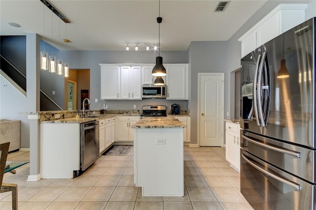 kitchen featuring pendant lighting, appliances with stainless steel finishes, a kitchen island, sink, and kitchen peninsula