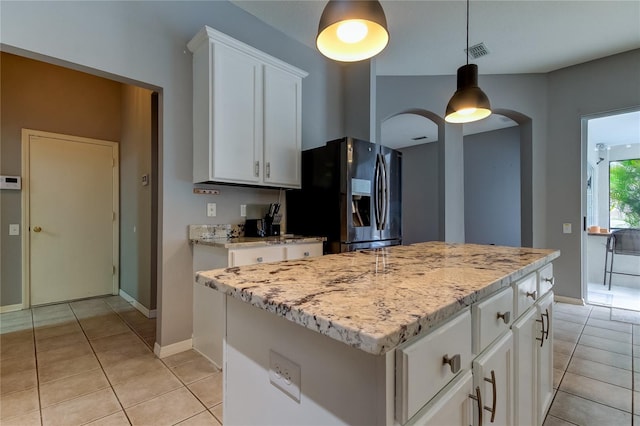 kitchen featuring light tile patterned floors, a center island, stainless steel refrigerator with ice dispenser, and pendant lighting