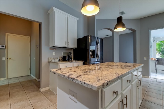 25954 Risen Star Dr, Wesley Chapel, FL 33544 - kitchen with a kitchen island, light stone countertops, white cabinets, and black fridge