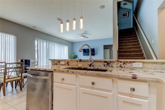 kitchen featuring ceiling fan, light tile patterned flooring, light stone counters, and stainless steel dishwasher