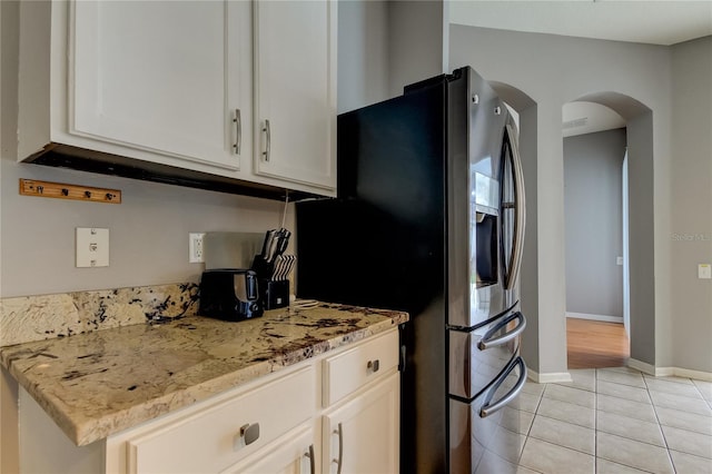 kitchen with stainless steel fridge with ice dispenser, light wood-type flooring, and light stone counters