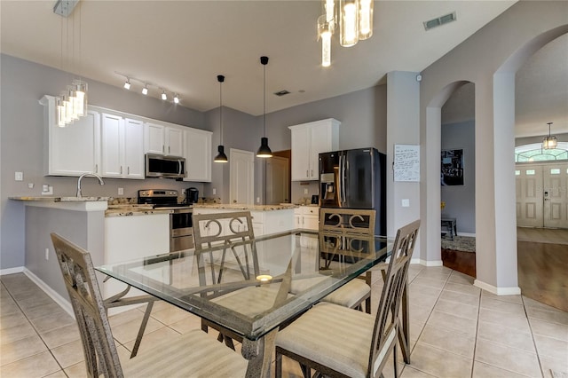 dining area with a notable chandelier, sink, light hardwood / wood-style flooring, and track lighting