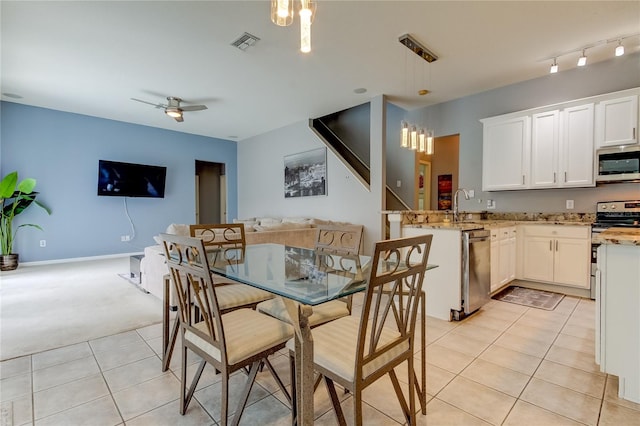 tiled dining area featuring sink, ceiling fan with notable chandelier, and track lighting