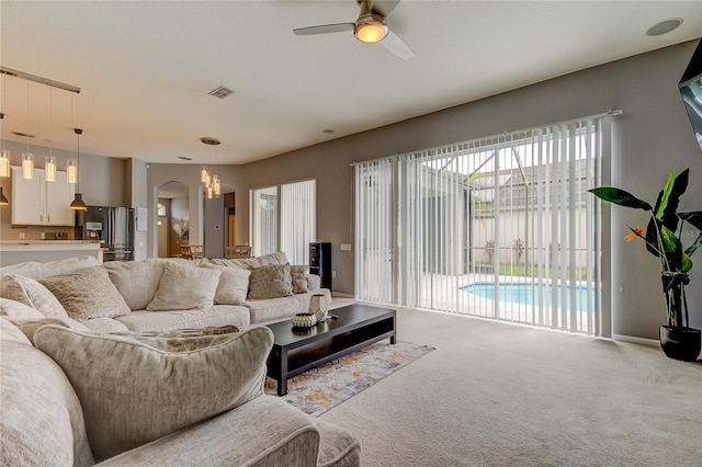 living room featuring light carpet, ceiling fan, and a healthy amount of sunlight