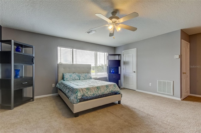 bedroom featuring ceiling fan, a textured ceiling, and light colored carpet