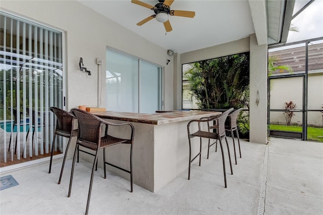 view of patio with ceiling fan and a bar