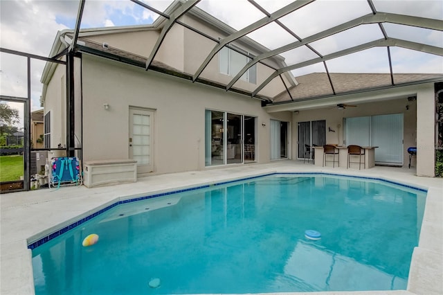 view of swimming pool with a patio area, glass enclosure, and ceiling fan