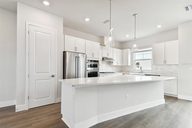 kitchen with decorative backsplash, a kitchen island, white cabinetry, and stainless steel appliances