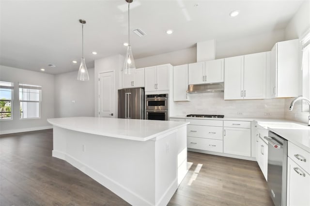 kitchen featuring white cabinetry, sink, stainless steel appliances, tasteful backsplash, and a kitchen island