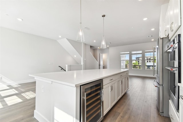 kitchen with hardwood / wood-style flooring, decorative light fixtures, a kitchen island, white cabinetry, and beverage cooler