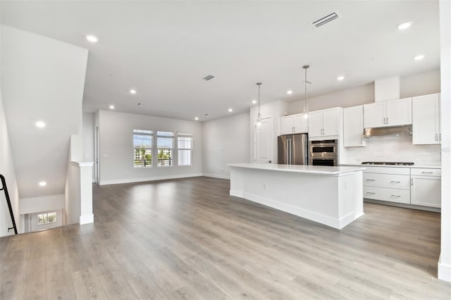 kitchen featuring a center island, light hardwood / wood-style floors, decorative light fixtures, white cabinets, and appliances with stainless steel finishes