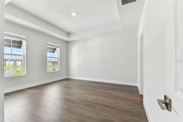 spare room with dark hardwood / wood-style flooring and a tray ceiling