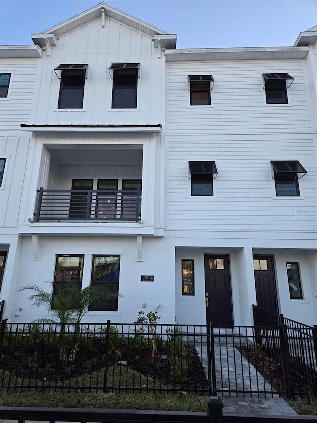 view of front of house featuring a fenced front yard, board and batten siding, and a balcony