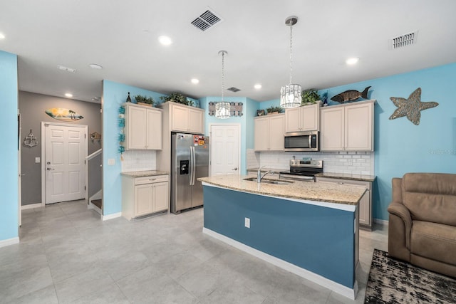 kitchen with sink, light stone counters, an island with sink, decorative light fixtures, and appliances with stainless steel finishes