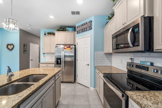 kitchen featuring decorative backsplash, stainless steel appliances, sink, light tile patterned floors, and decorative light fixtures