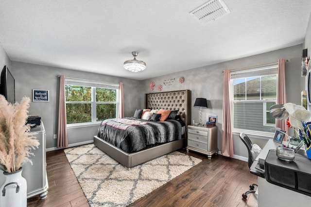 bedroom featuring a textured ceiling, dark hardwood / wood-style floors, and multiple windows