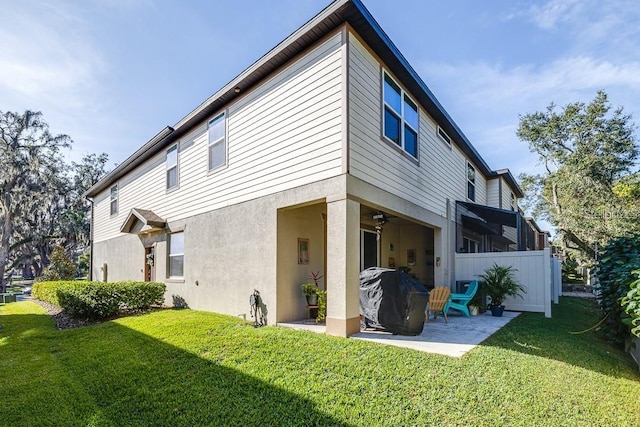 back of property with ceiling fan, a yard, and a patio